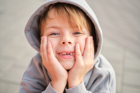 Handsome smiling little boy on the sunny urban background . Close-up portrait. Blond hair, blue eyes...