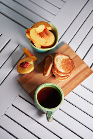 Simple, sweet and Tasty breakfast. Pancake on a wooden plate with peach and coffee in a beautiful ceramic pottery. Weekend morning vibe. High quality photoの写真素材