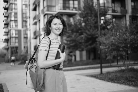Summer sunny lifestyle portrait of stylish hipster woman walking on the street, wearing cute trendy outfit, smiling enjoy her weekends, travel with bag. High quality photoの写真素材