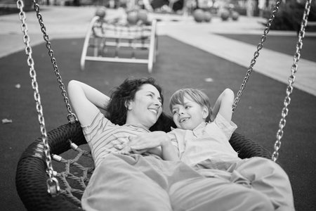 Happy Young mother playing with her son on the playground, hugging, laughing. having fun together on the weekend sunny day. School playground. High quality photoの写真素材