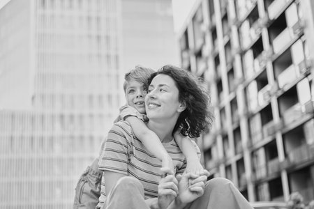 young mother and son smiling looking at the camera in modern residential complex. Having fun together, happy parenting, new home concept. Bright summer day in the urban background. High quality photoの写真素材