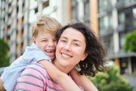 young mother and son smiling looking at the camera in modern residential complex. Having fun together, happy parenting, new home concept. Bright summer day in the urban background. High quality photoの写真素材