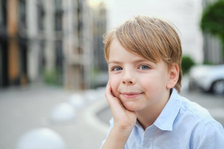 Handsome smiling little boy on the sunny urban background . Close-up portrait. Blond hair, blue eyes , 9 years boy smiling, having fun in the city. High quality photoの写真素材