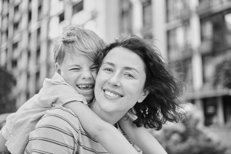 young mother and son smiling looking at the camera in modern residential complex. Having fun together, happy parenting, new home concept. Bright summer day in the urban background. High quality photoの写真素材
