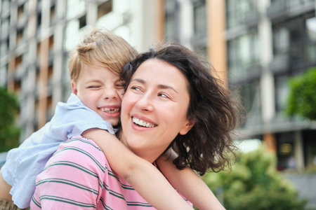 young mother and son smiling looking at the camera in modern residential complex. Having fun together, happy parenting, new home concept. Bright summer day in the urban background. High quality photoの写真素材