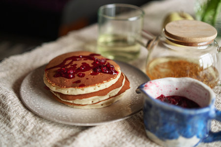 Simple pancake breakfast with jam and apple, tea served on a kitchen table. Simple life concept High...