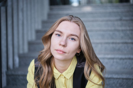 Beautiful blond female office worker on the background of office building . Positive emotions, wearing yellow shirt and jacket. High quality photoの写真素材