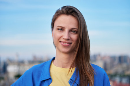 Young female dressed in national colours of Ukraine on the Kyiv city scape. Independent concept, support Ukraine, stop war. High quality photoの写真素材