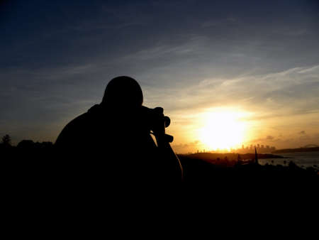Photo presents a person who takes a picture at sunset background.の写真素材