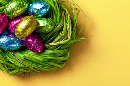 Colorful easter eggs in green nest  Holiday chocolate background  Top view  Macro shotの写真素材