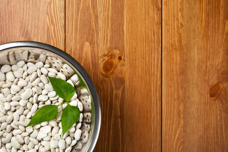 White beans in colander on wooden table background. Top viewの写真素材
