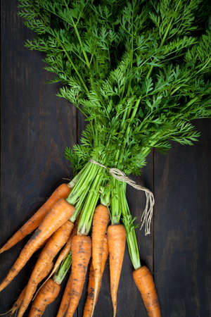 Fresh carrots bunch on wooden table background. Top viewの写真素材
