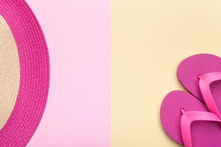 Summer concept. Beach hat and flip flops on pink and yellow background. Flat lay. Minimal style.の写真素材