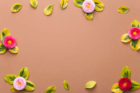 Daisies with leaves on brown background. Flat lay. Copy space. Top viewの写真素材