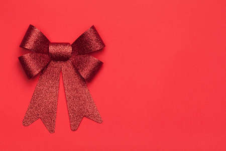 Christmas background with red bow on red paper background. Copy space. Top viewの写真素材