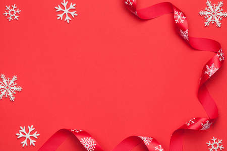 Christmas background with snowflakes and ribbon on red paper. Copy space. Top viewの写真素材