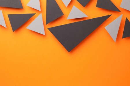 Black and gray triangular shapes on orange paper background. Abstract composition with empty room...