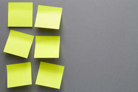 Yellow sticky notes on grey paper background. Empty room for text. Top viewの写真素材
