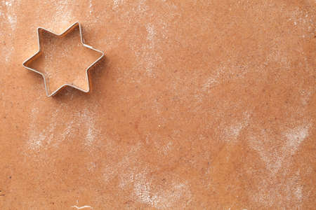 Christmas cookie cutter in shape of star over homemade gingerbread dough. Top view. Copy spaceの写真素材