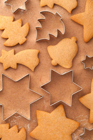 Sweet christmas background with homemade gingerbreads and cookie cutters over gingerbread dough. View from aboveの写真素材