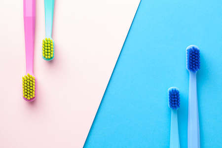 New toothbrushes on pink and blue paper background. Man and woman teeth hygiene. Top viewの写真素材