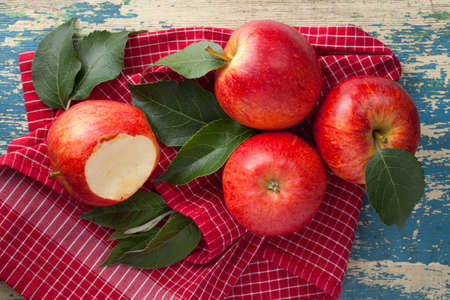 Red gala apples composition with fresh green leaves on red and white checkered napkin. View from aboveの写真素材