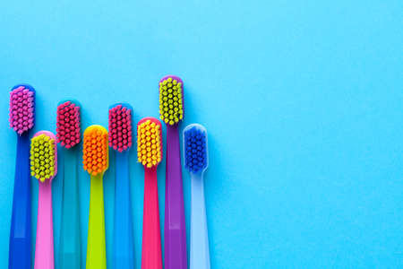 Colorful toothbrushes over blue paper background. Empty room for text. Top viewの写真素材