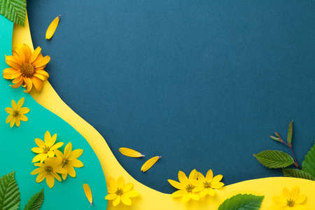 Composition with natural flowers and leaves on paper background. Colored paper layers cut out in...