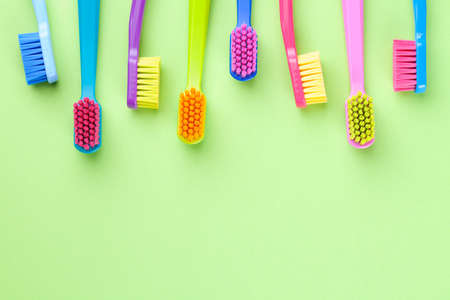 New toothbrushes set on green paper background. Copy space. Top view
