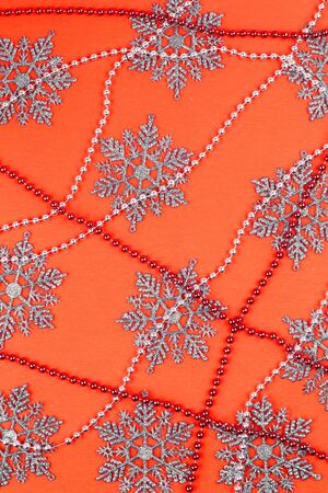 Orange paper background with the sparkling snowflakes and beadsの写真素材