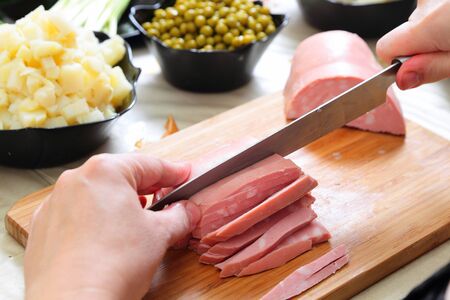 Preparing russian traditional salad Olivier, chopping sausageの写真素材