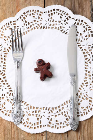 Chocolate man with fork and knife on a wooden tableの写真素材
