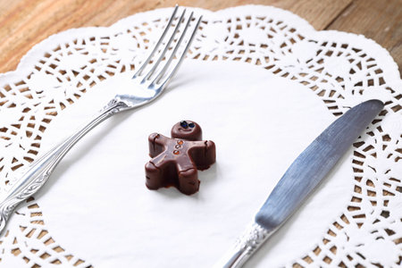 Chocolate man with fork and knife on a wooden tableの写真素材