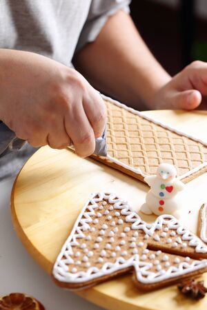 Making of christmas gingerbread house. Roof decorating. Close up view with selective focus.