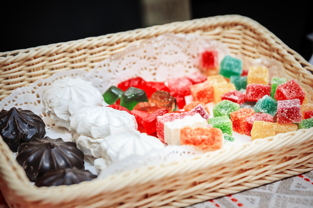 Assortment of homemade confectionery in the wicker basket. Marshmallow, zephyr, marmalade, jellyの写真素材