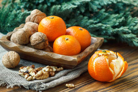 Christmas New Year composition with tangerines, nuts, pine cones and fir branches in rustic style on old wooden background, selective focusの写真素材
