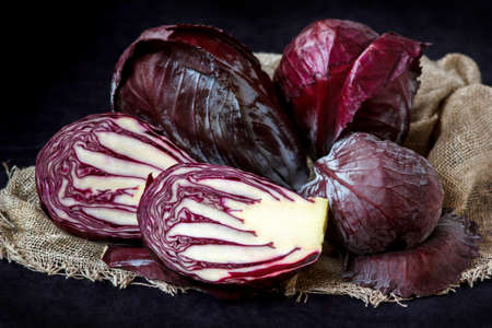 Whole And Cut In Half Fresh Red Cabbage In A Wooden Plate on Dark Backgroundの写真素材
