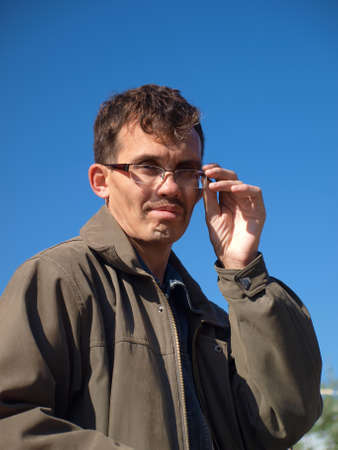 The adult dark-haired short-sighted man on the blue