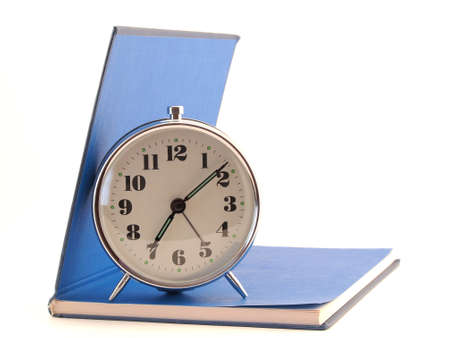 The alarm clock standing on the open blue book