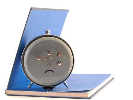 The alarm clock standing on the open blue bookの写真素材