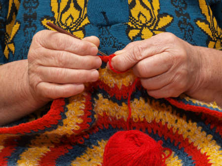 Hands of the elderly woman knitting by means of a hookの写真素材