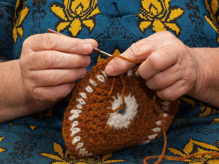 Hands of the elderly woman knitting by means of a hookの写真素材
