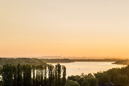 early morning on the river bank. view of the river with a small hill in the background city outlinesの写真素材