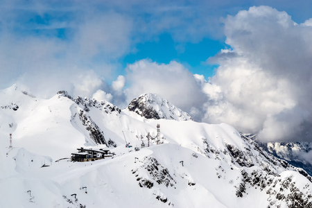 The snow capped mountains are covered with thick clouds with small wooden house on topのeditorial素材