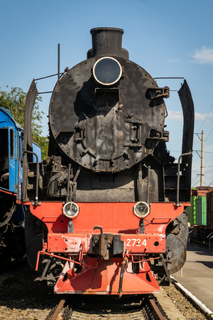 Old steam locomotive beside a railway station platform. Retro train.のeditorial素材