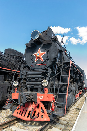 Old steam locomotive beside a railway station platform. Retro train.のeditorial素材