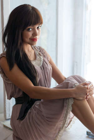 Gorgeous young brunette sitting near of window, natural lightの写真素材