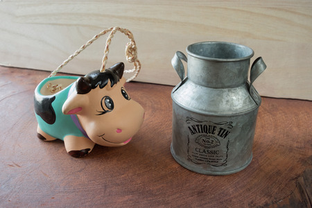Pottery cow pot want to drink milk in milk bucket on wooden table Pottery cow pot want to drink milk in milk bucketの写真素材