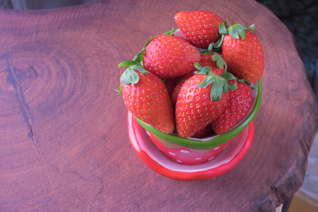 Fresh red strawberry in strawberry pot on red brown wooden tableFresh strawberry in strawberry cupの写真素材