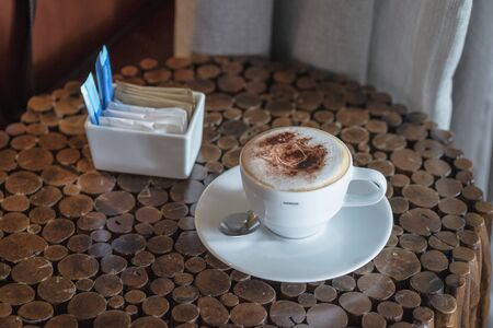Hot coffee in white cup and saucer with silver spoon on wooden tableの写真素材